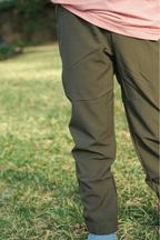 Boy wearing forest green pants standing in a grassy field