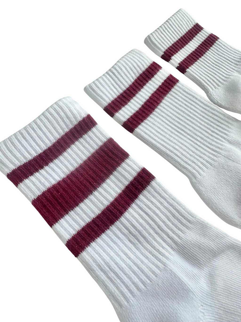 Close up shot of three white boys socks with maroon stripes on a white background