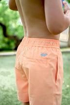 Boy wearing Tarry's orange swim shorts outdoors